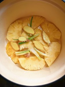 Add a thin layer of oil to the pot, then scatter in the ginger, scallion segments, and pineapple.
