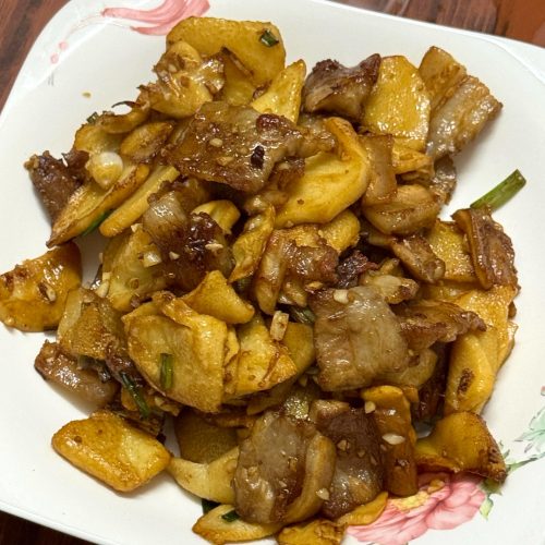 Pork belly and bamboo shoots stir-fried in a wok