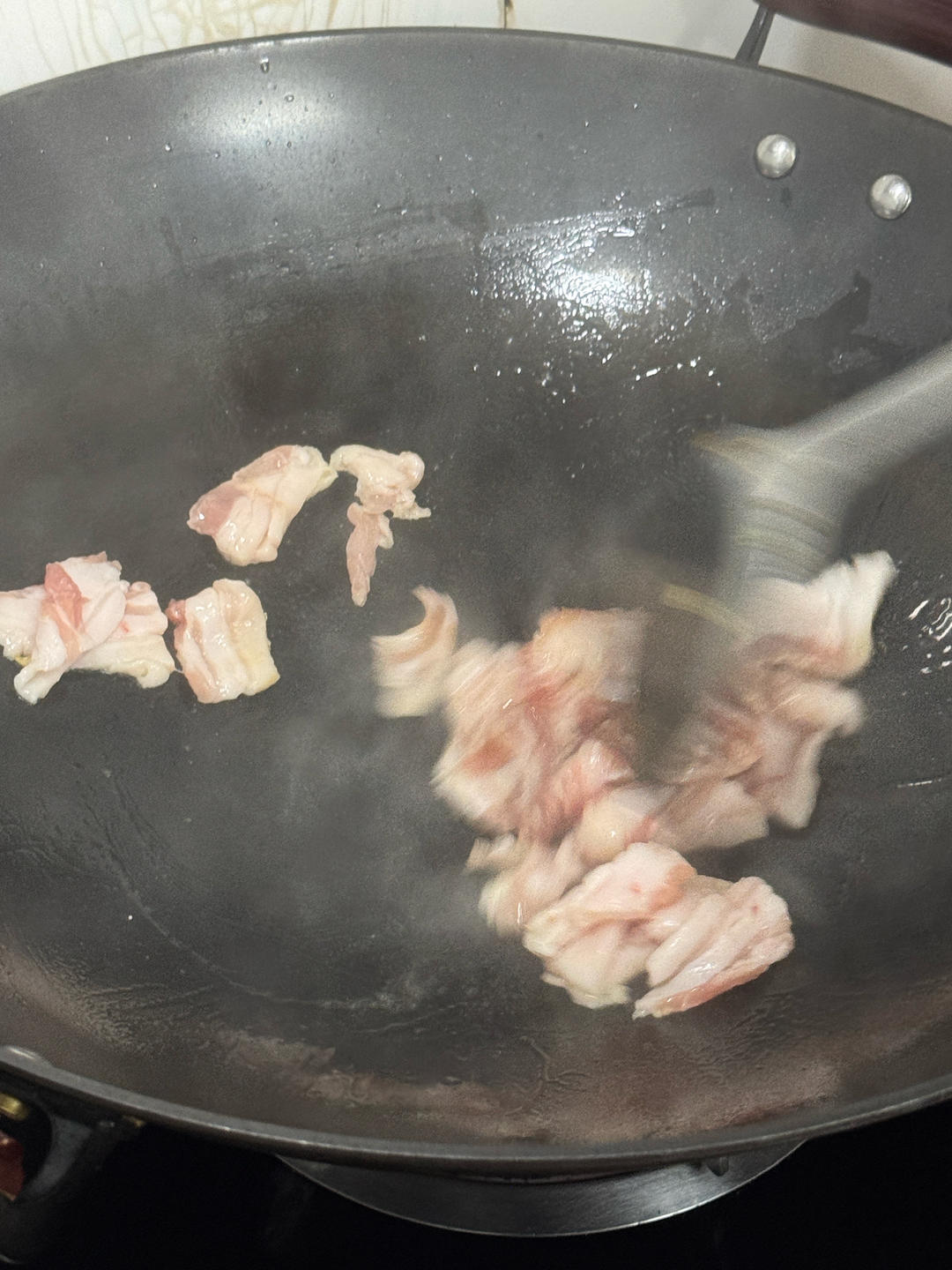 Sliced pork belly rendering in the wok