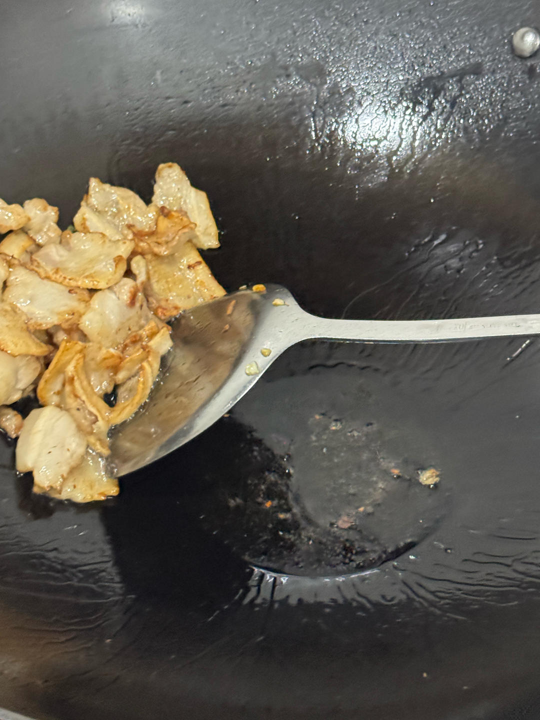 Excess rendered fat being spooned out of the wok