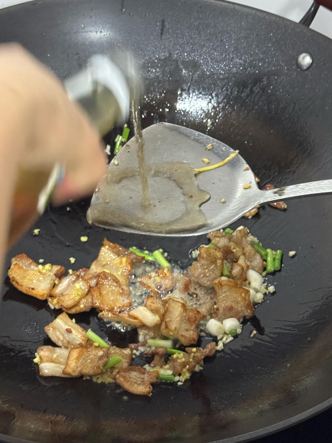 Shaoxing wine being poured down the side of the wok