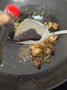 Light soy sauce being stirred into the pork