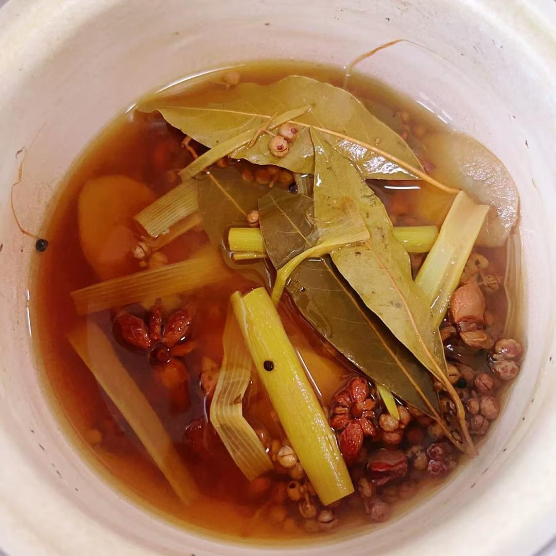 Simmer 2 pieces of scallion, 20 g sliced ginger, 4 star anise, 2 tsp Sichuan peppercorns, 4 bay leaves, and water until fragrant and the liquid turns brown; turn off the heat and l