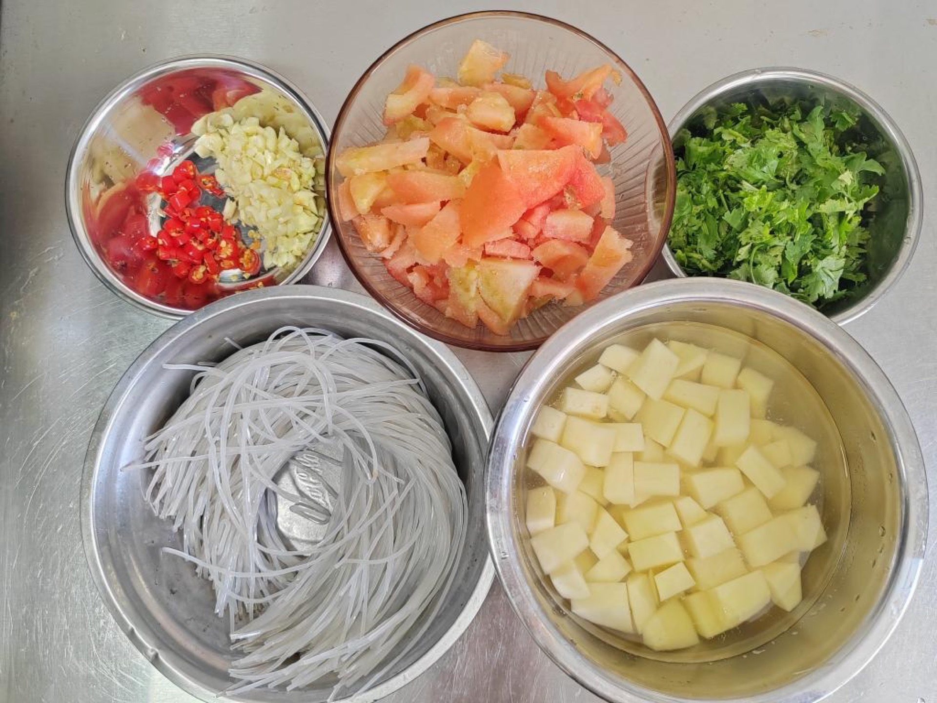 Chopped potatoes, tomatoes, garlic and chilies prepped on a board