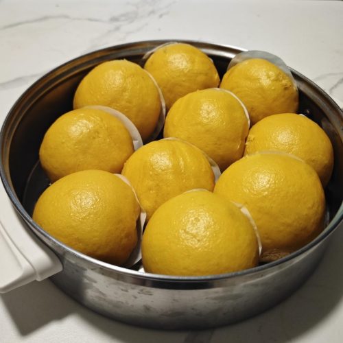Golden pumpkin butter steamed buns stacked in a bamboo steamer