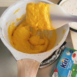Pumpkin cream cheese filling cooking down in a small saucepan