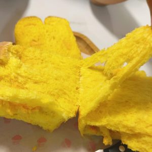 A torn piece of pumpkin cheese toast showing the swirl