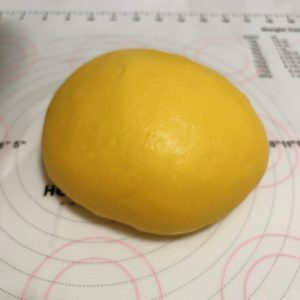 Two rounded balls of pumpkin dough resting under cover