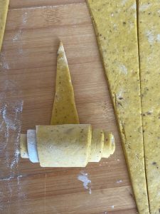 Rolling a dough triangle from the wide end into a horn shape