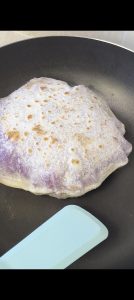 Purple sweet potato pancakes frying until golden