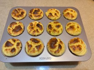 Freshly baked puffed durian cheesecake cups on a rack