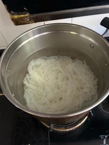 Fresh rice noodles blanching in a pot of boiling water