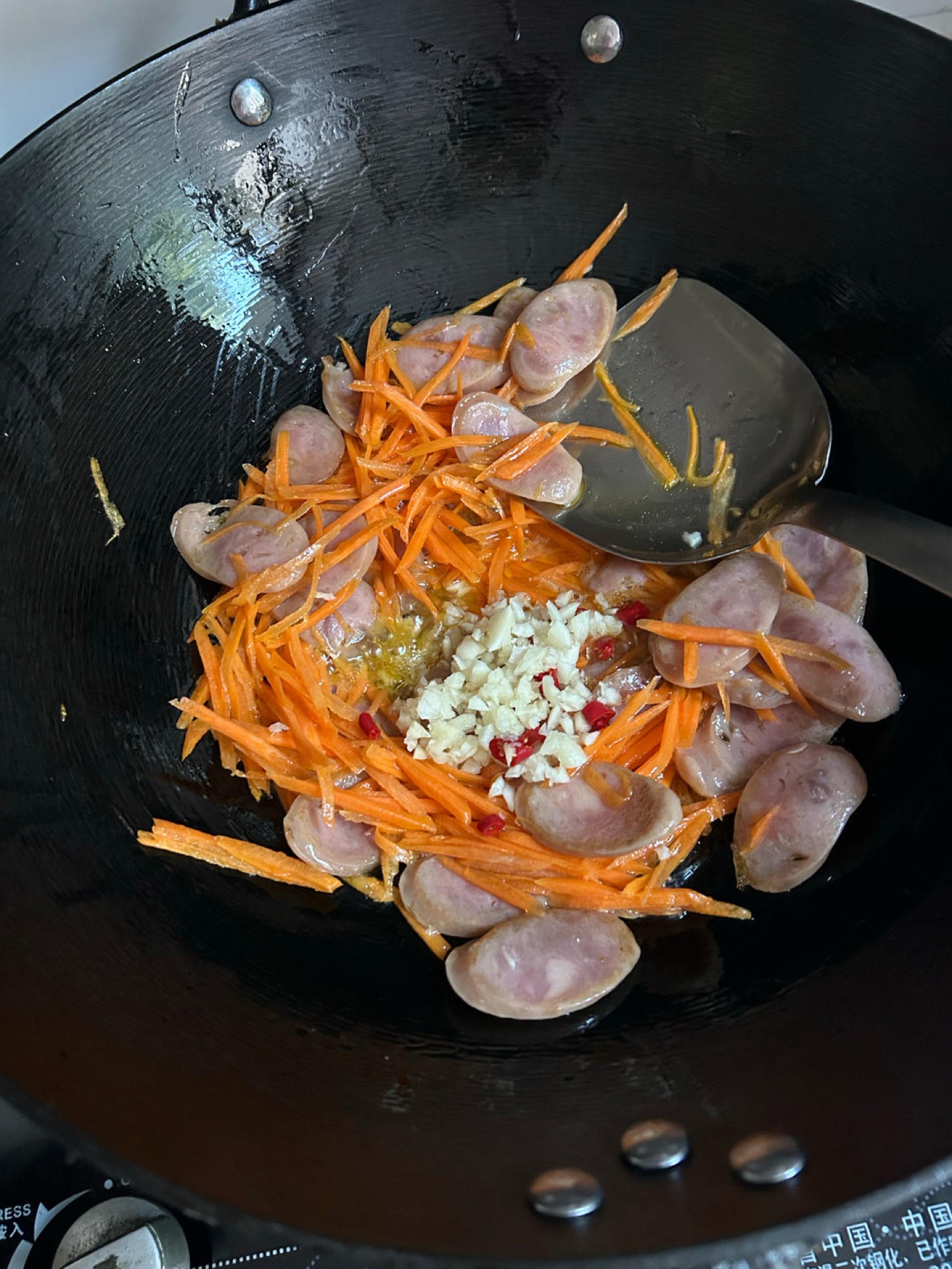 Carrot, garlic, chili, and Chinese sausage stir-frying in a hot wok