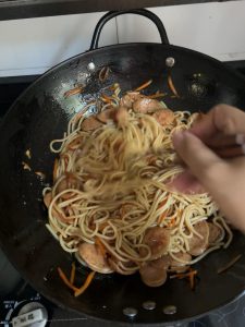 Glossy rice noodles evenly coated in soy sauce in a wok