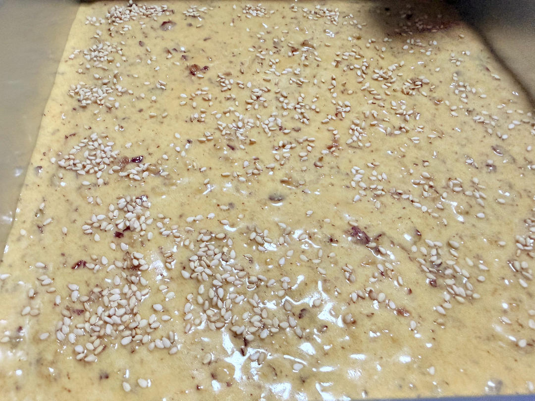Pouring the batter into the pan and sprinkling sesame