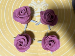 The rose bun placed on the crossed green dough leaves