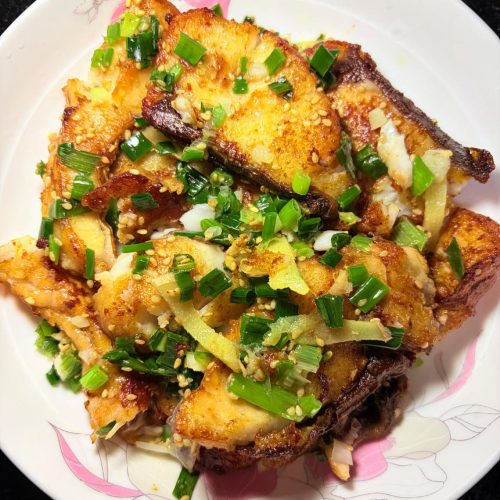 Scallion braised grass carp pieces in a wok with salt-scallion sauce