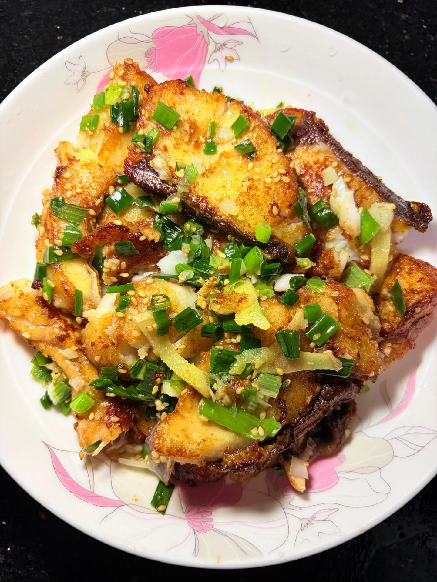 Scallion braised grass carp pieces in a wok with salt-scallion sauce