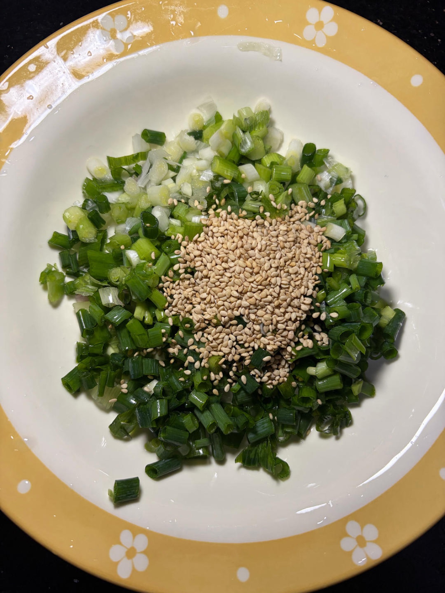 Rinse a bunch of scallions clean and chop them into small pieces, add 2 tbsp white sesame seeds, and if you like heat add chopped bird's eye chilies — I left them out because kids