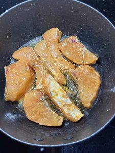 Leave a little oil in the wok, add the marinated fish pieces without moving them, and sear until one side is set and golden before flipping.