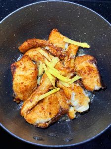 Add the julienned ginger, splash a little Shaoxing wine around the edge of the wok to boost aroma and cut the fishiness, and toss briefly.