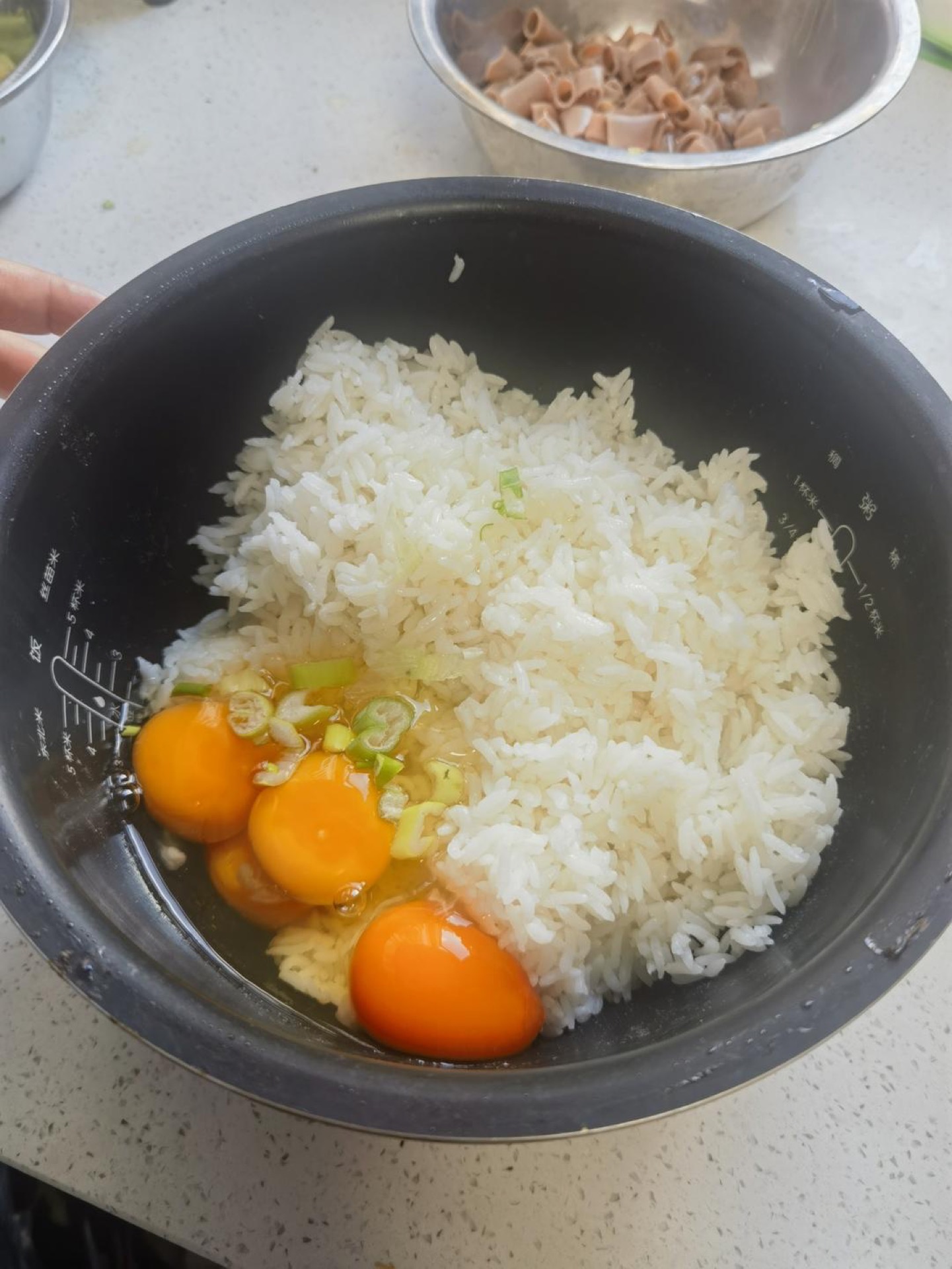 Cooked rice mixed with beaten egg and scallions in a bowl