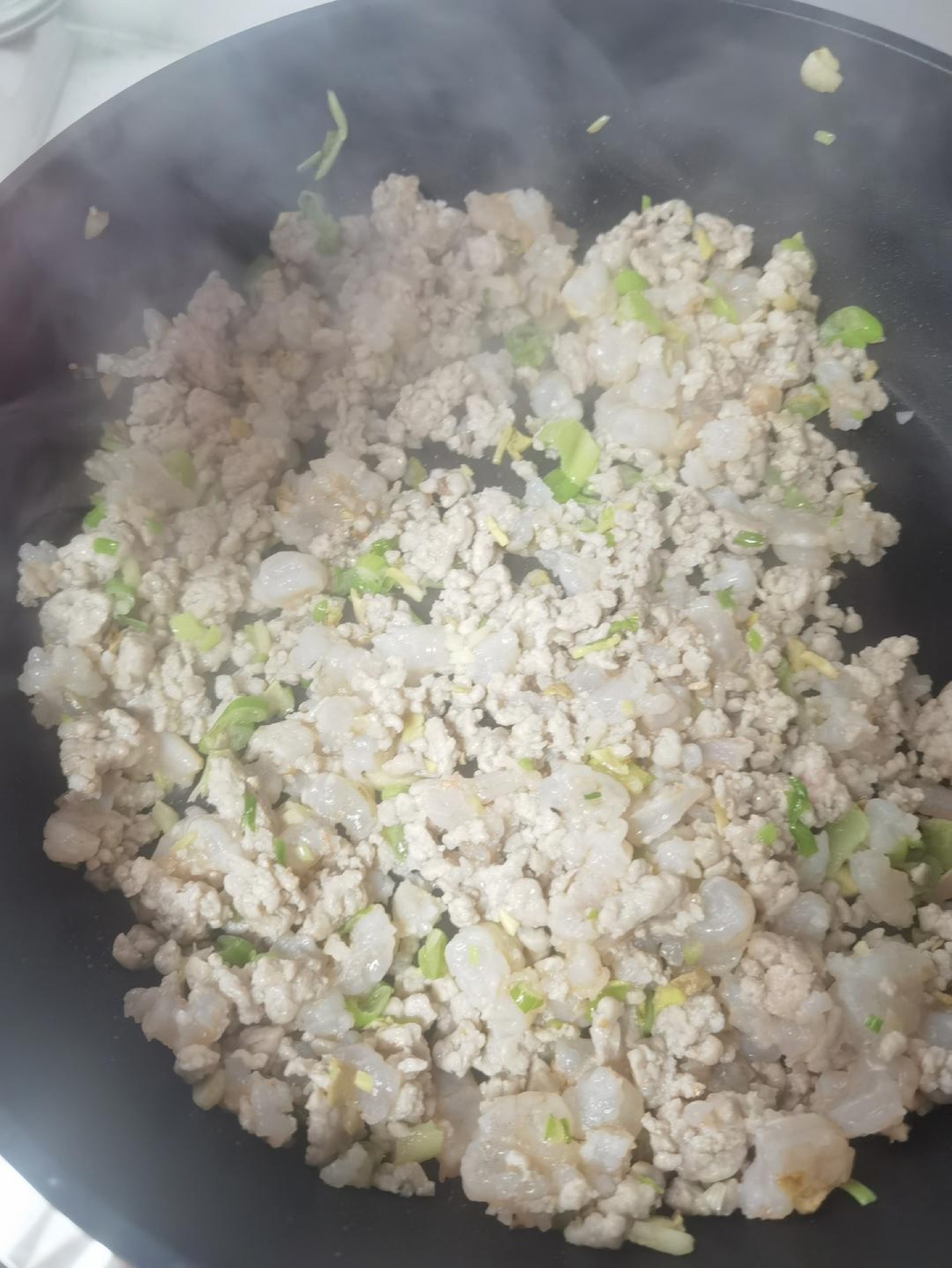 Ground pork and diced shrimp stir-frying in a wok