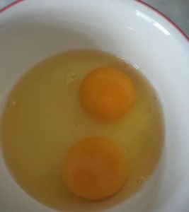 Crack two eggs into a bowl.