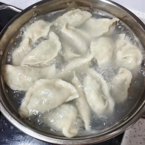 Spanish mackerel dumplings (鲅鱼水饺) piled on a plate with black vinegar dipping sauce