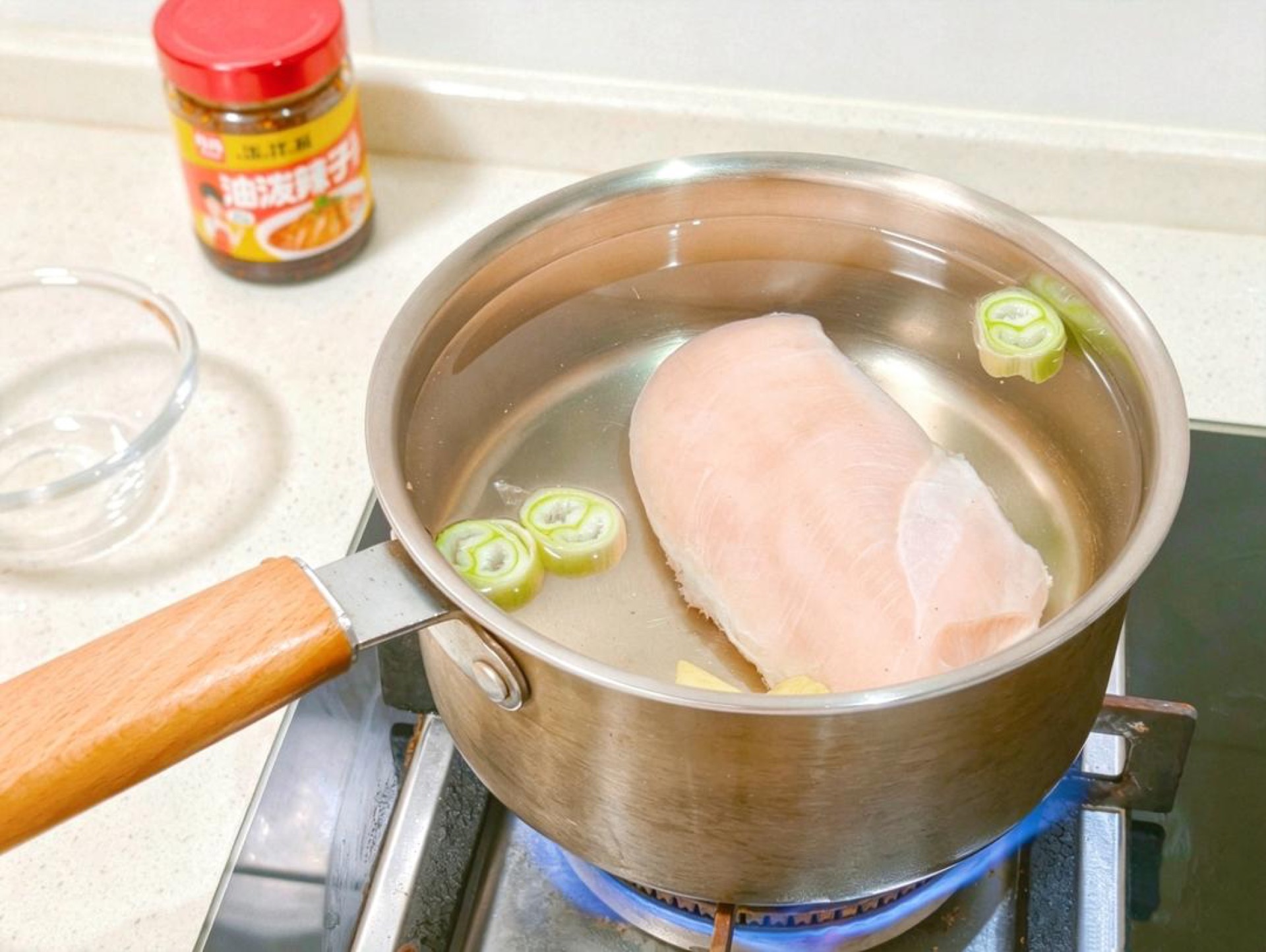 Place the chicken breast in a pot and add cold water to cover it by about an inch, then add the ginger slices, scallion segments, and Shaoxing wine.