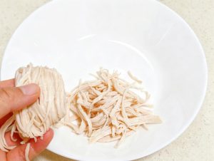 Lift the cooled breast from the ice water, pat it dry, and tear it apart along the grain into fine, even shreds with your fingers.