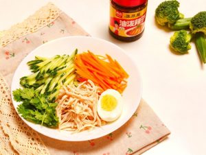 Julienne the cucumber and carrot into fine matchsticks and spread them across the bottom of a serving bowl, then halve the hard-boiled egg and set it aside.