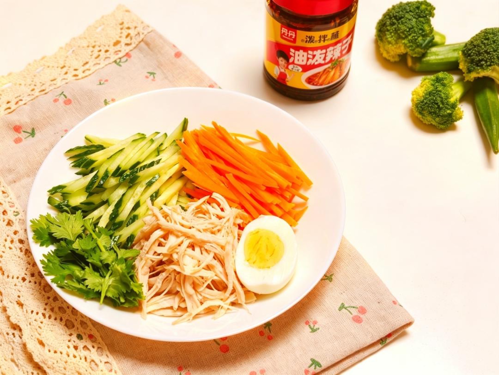 Julienne the cucumber and carrot into fine matchsticks and spread them across the bottom of a serving bowl, then halve the hard-boiled egg and set it aside.