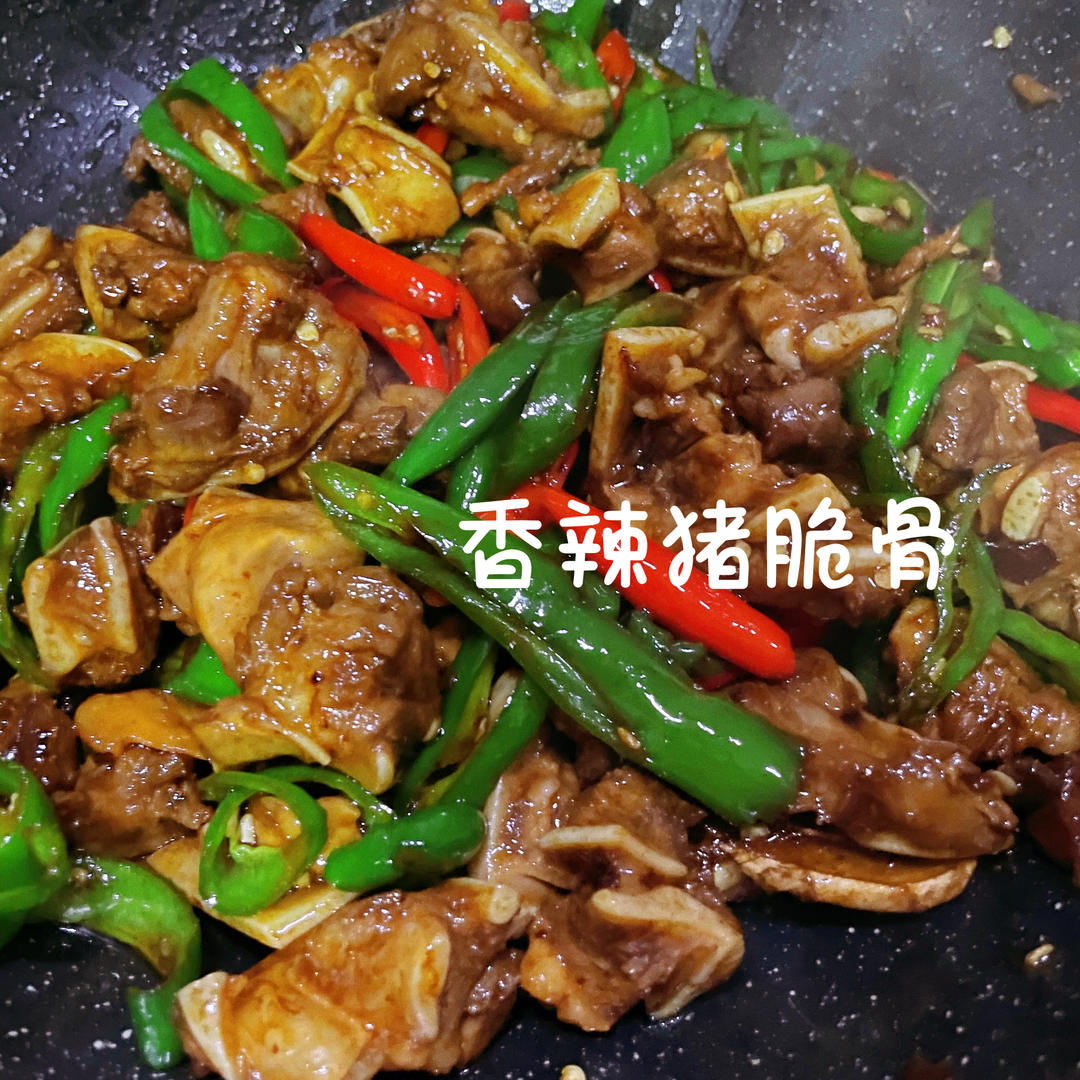 Glossy spicy stir-fried pork cartilage with chilies in a dark bowl