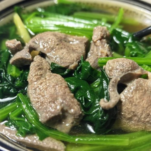 Clear Chinese spinach and pork liver soup in a bowl