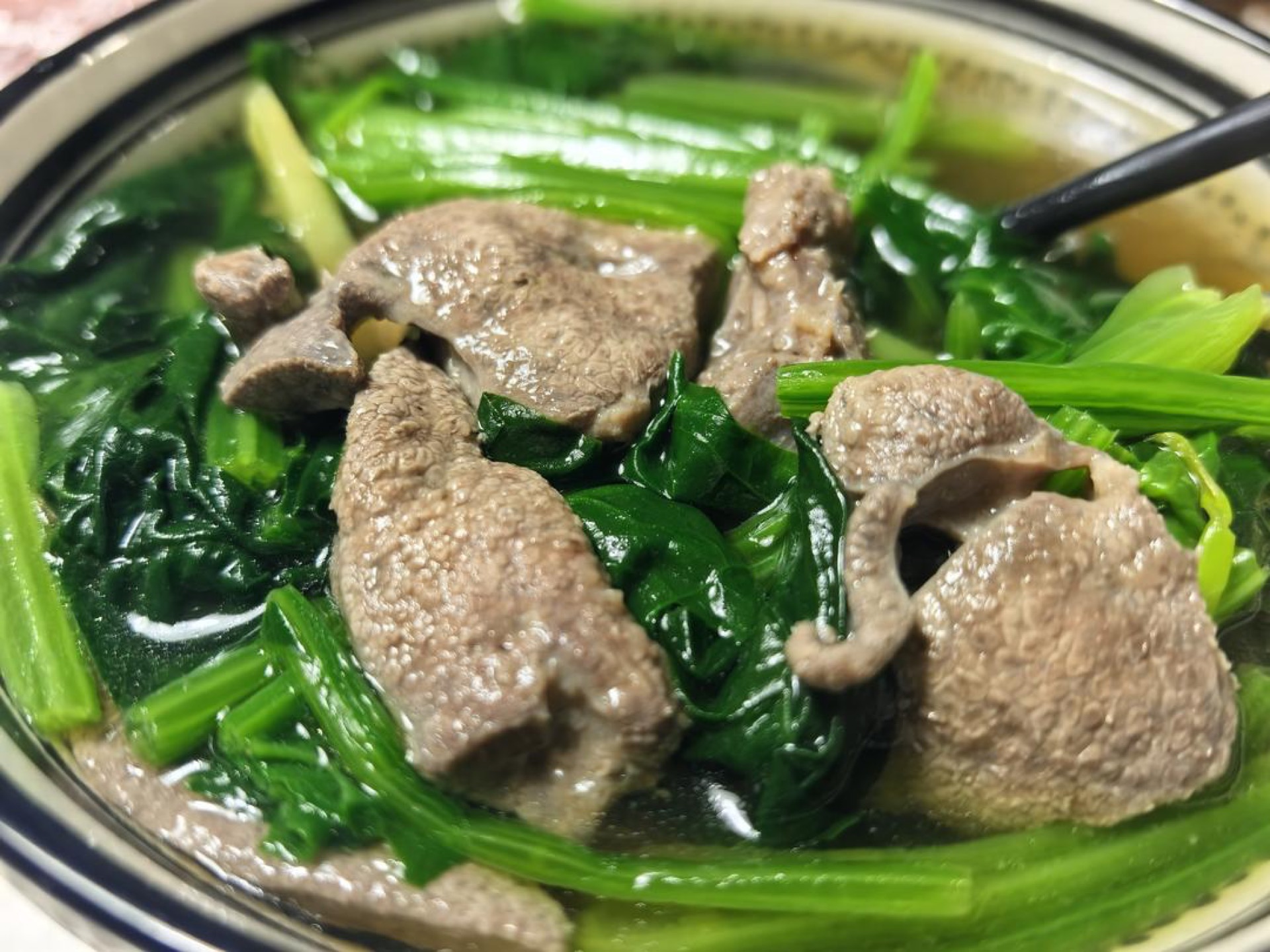 Clear Chinese spinach and pork liver soup in a bowl