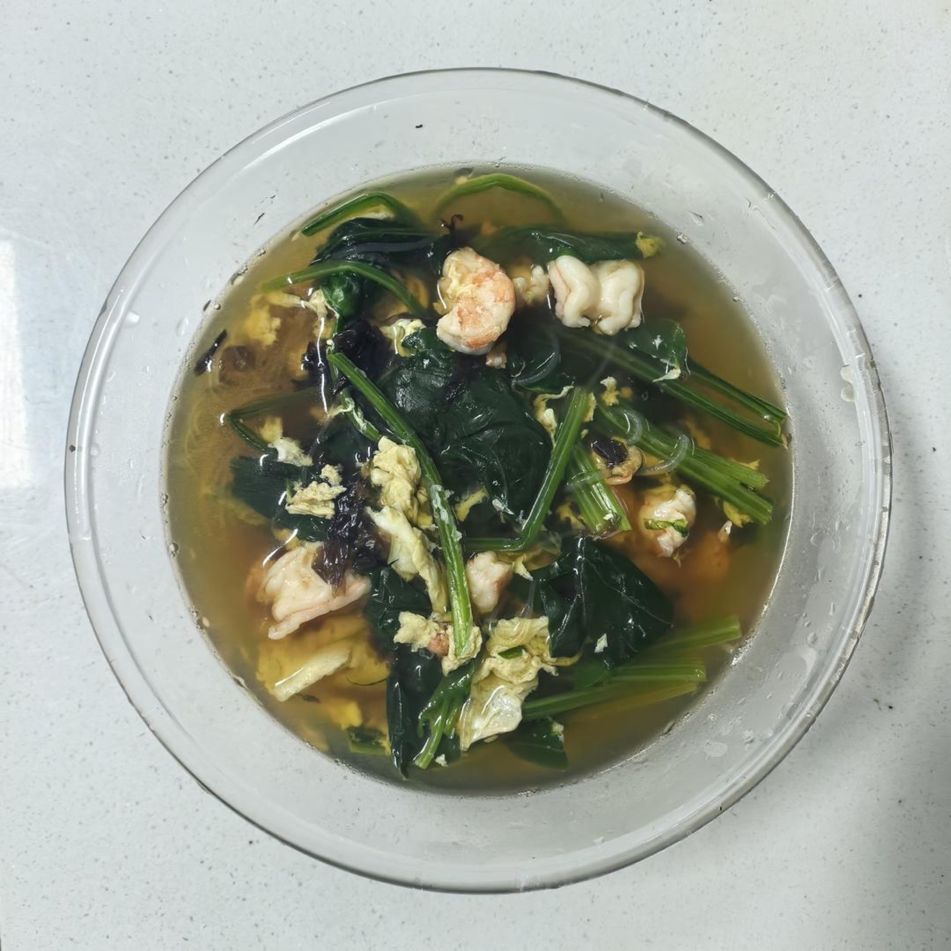A bowl of spinach soup with shrimp and vermicelli (菠菜汤) with egg ribbons, nori, and dried shrimp