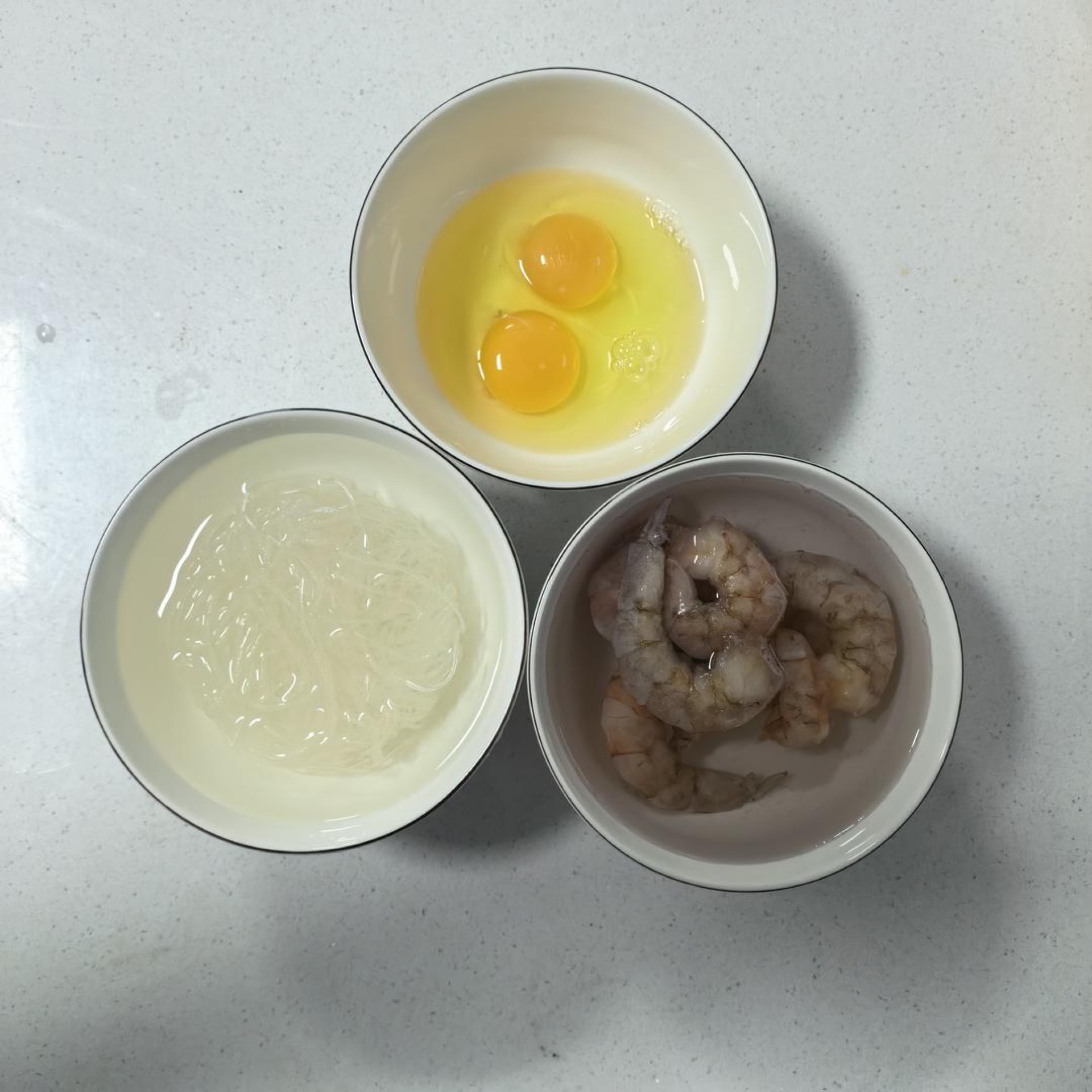 Soak the frozen shrimp to thaw, soak a bundle of vermicelli in warm water until pliable, and beat two eggs in a small bowl.