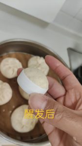 Proofed dough risen above the rim of the small cup