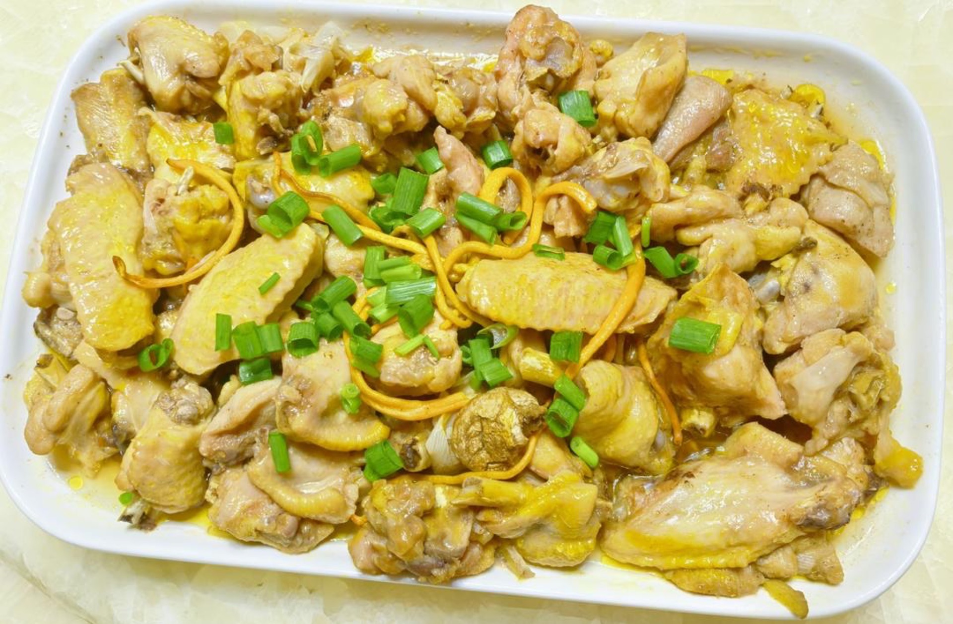 Steamed chicken with cordyceps flowers (虫草花蒸鸡) in a white steaming dish, garnished with chopped scallion