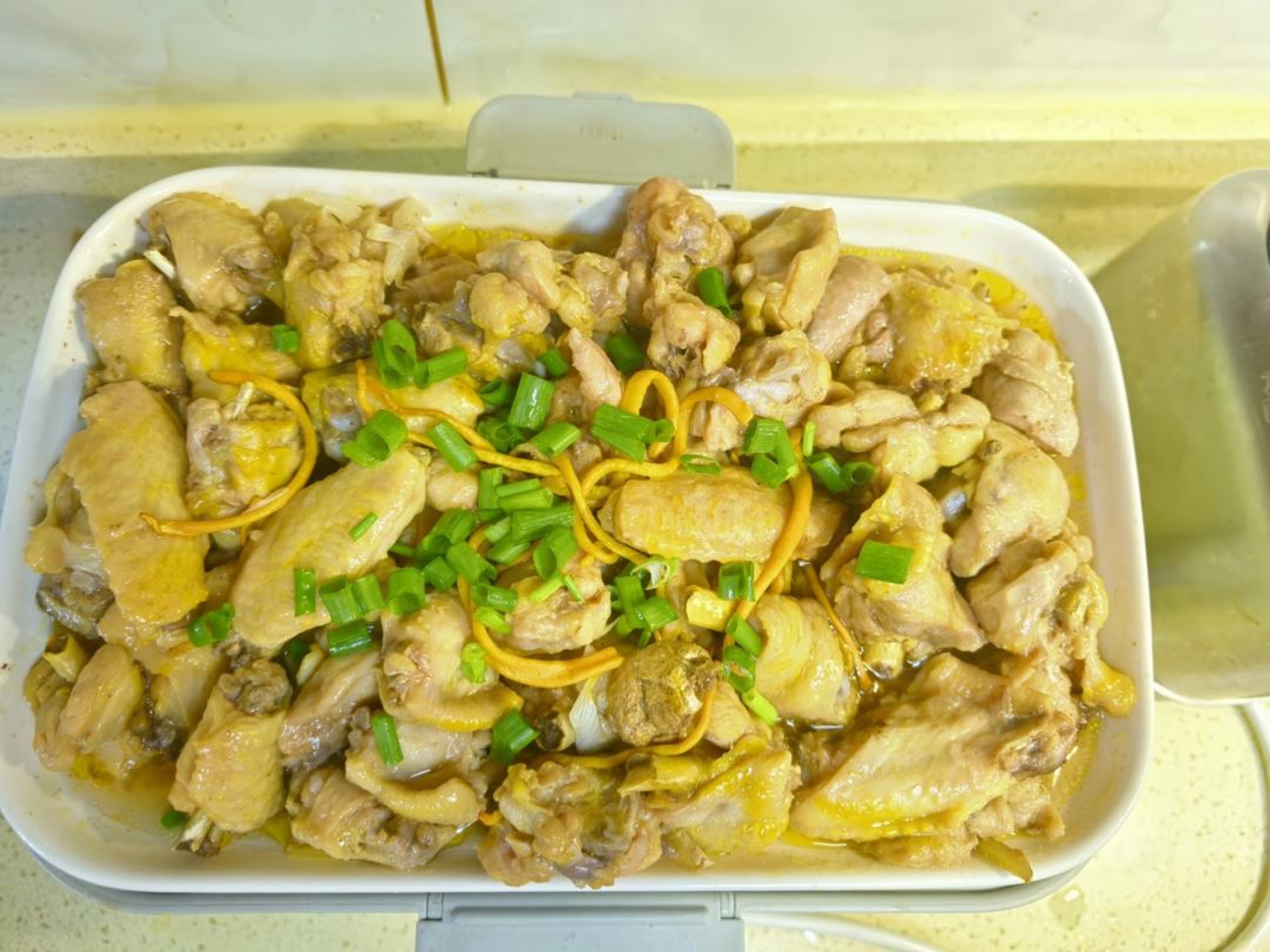 When the time is up the steamer beeps and switches to keep-warm, so open the lid, scatter over chopped scallion, and add a few goji berries if you want extra color — the chicken is