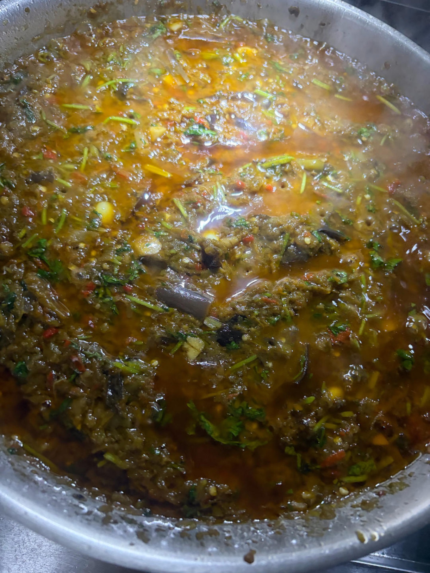 Once the oil is hot, add the chilies, cilantro, eggplant, ginger, and garlic to the wok and stir-fry until everything is evenly combined.