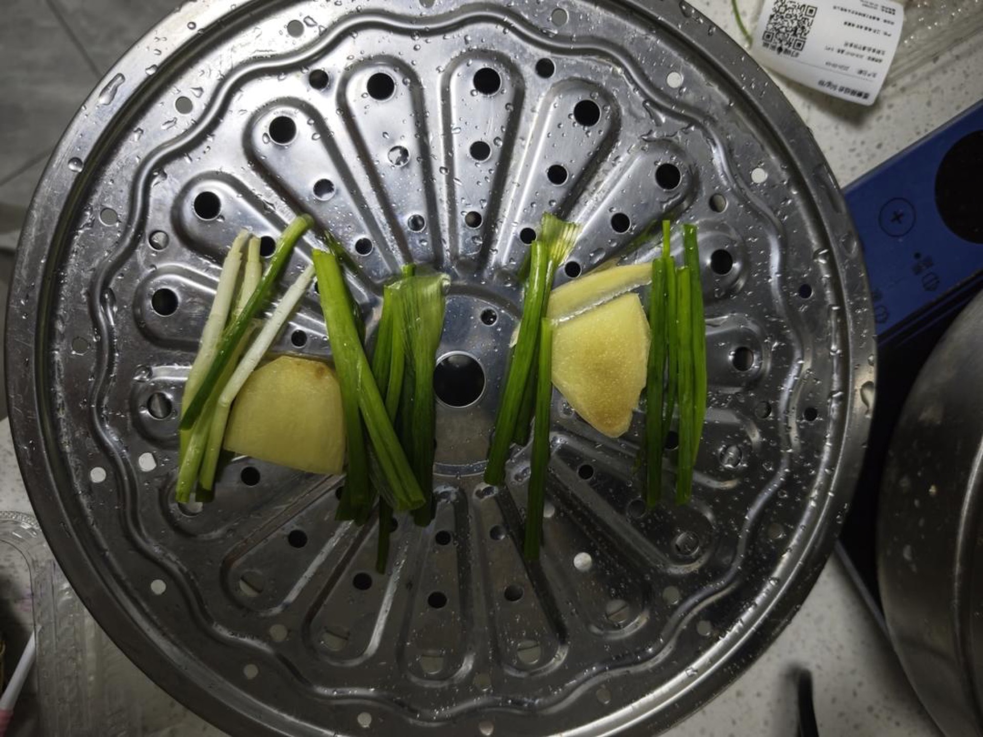 Scallions and ginger laid on a steamer rack