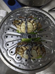 Cleaned crabs arranged belly-up on the steamer rack