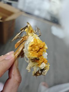 Steamed hairy crab broken open showing orange roe, with dipping sauce
