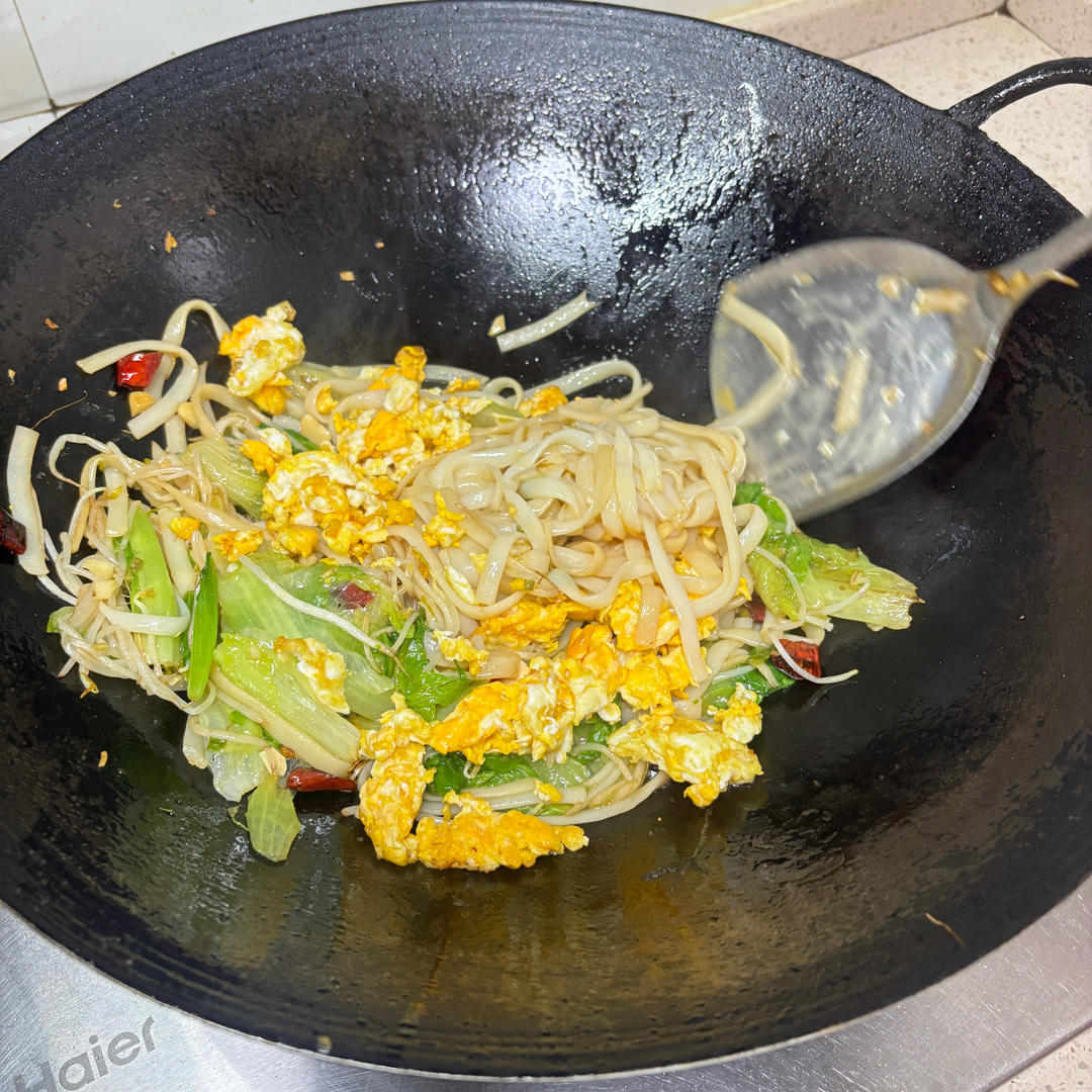 Returning the egg to the wok with the noodles