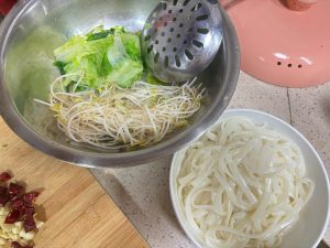 Rinsing the ho fun and vegetables in hot water