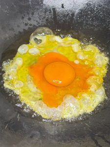 Frying the egg in the hot wok