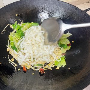 Adding sprouts greens and ho fun to the wok in order