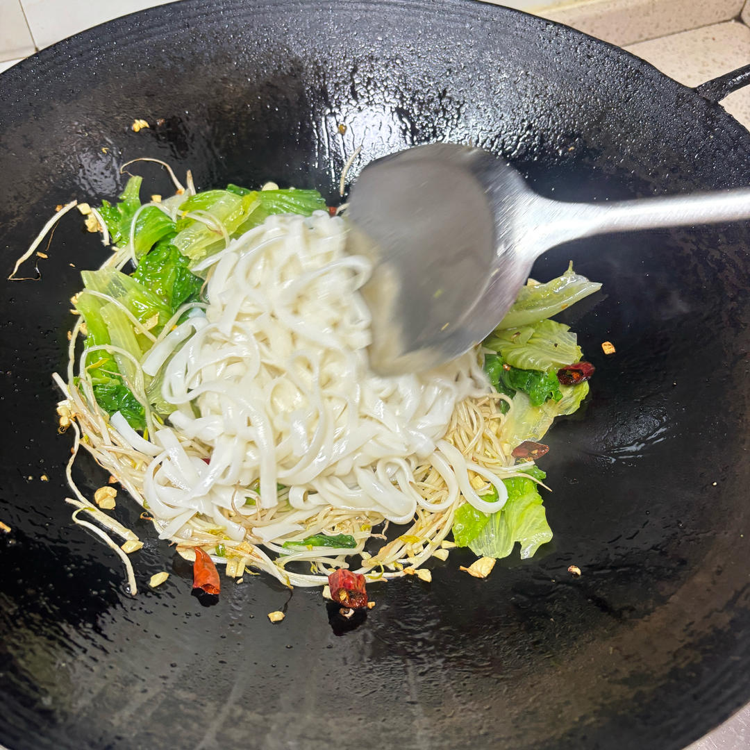 Adding sprouts greens and ho fun to the wok in order